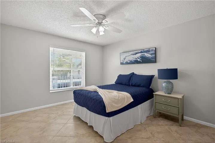 Guest bedroom with a ceiling fan/light and tile floors.