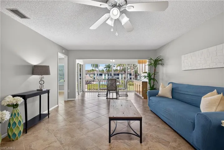 Living room with views of the pool and courtyard, ceiling fan/light and matching tile floors throughout