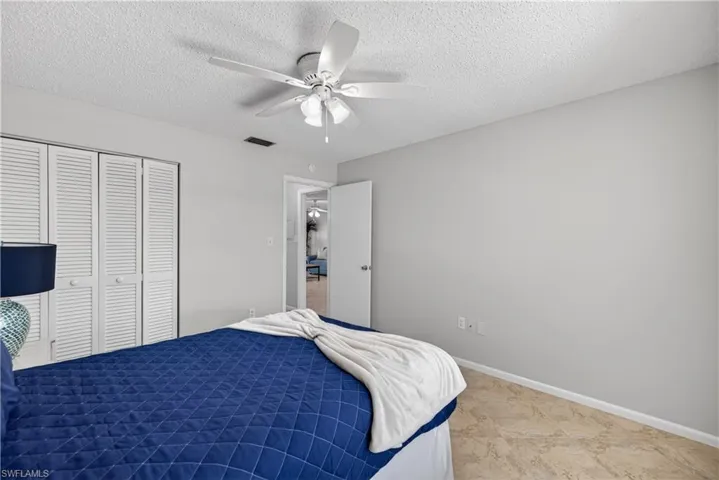 Guest bedroom with a ceiling fan/light and tile floors.