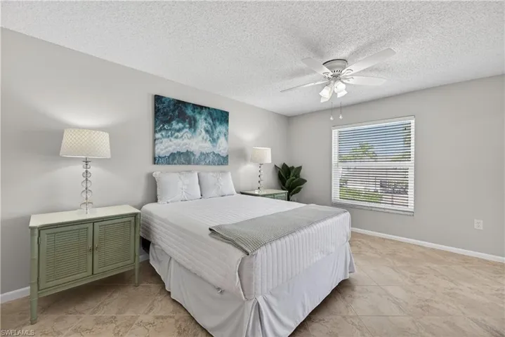 Bedroom featuring a ceiling fan/light, tile floors and views of the courtyard and pool.