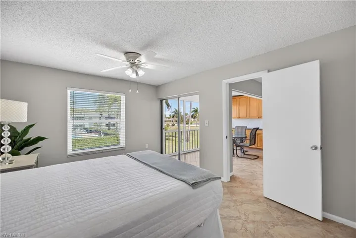 Bedroom featuring a ceiling fan/light, tile floors and views of the courtyard and pool.