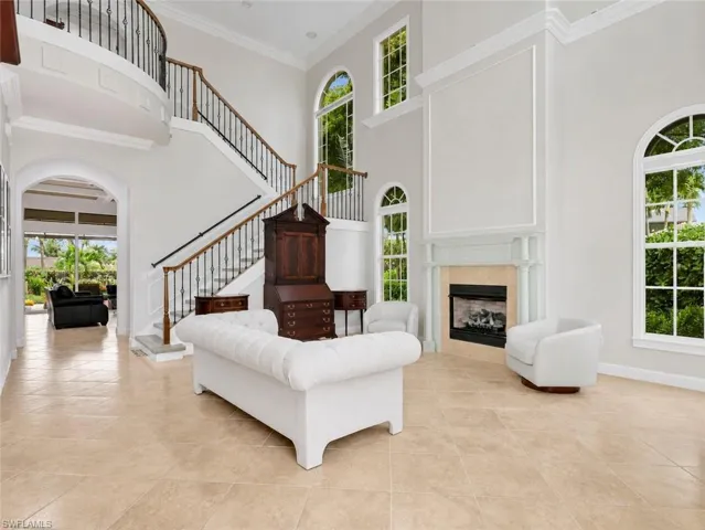 Living room with gas fireplace, crown molding, and tile floors