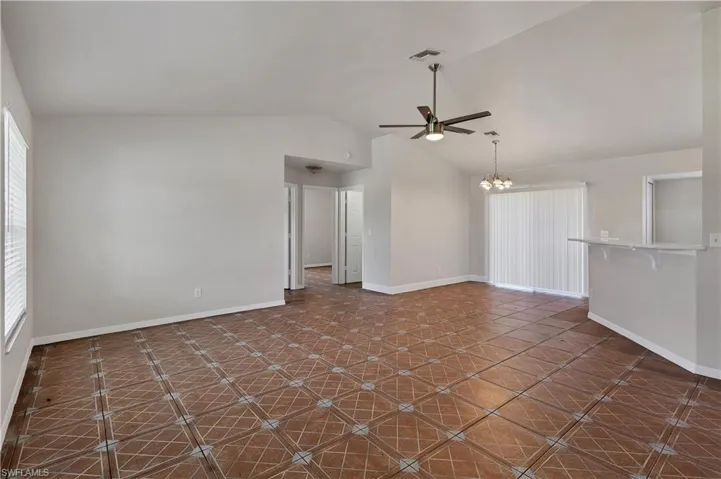 Vaulted ceilings with a ceiling fan, patterned tile flooring, and a breakfast bar