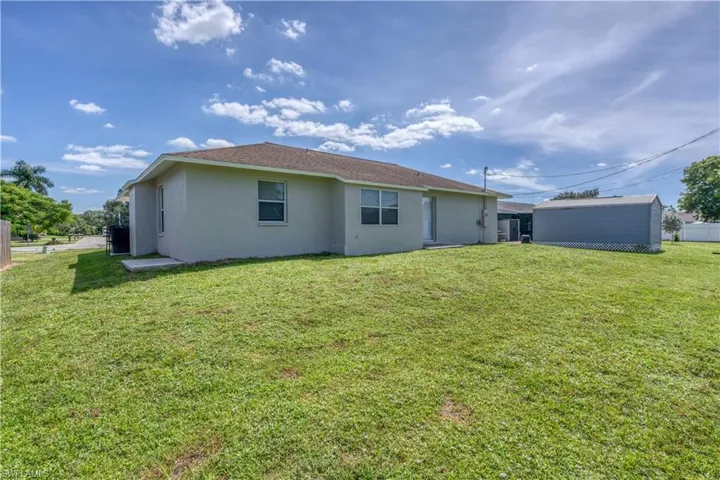 Expansive green space featuring a detached storage shed, privacy fencing, and mature landscaping