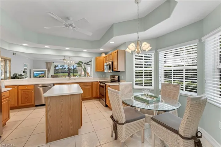 Kitchen featuring light countertops, a kitchen island, appliances with stainless steel finishes, ceiling fan with notable chandelier, and recessed lighting