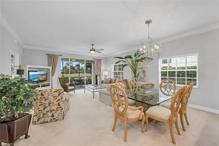 Dining space with light carpet, baseboards, and crown molding