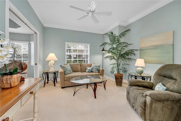 Living area featuring ceiling fan, plenty of natural light, crown molding, and light colored carpet