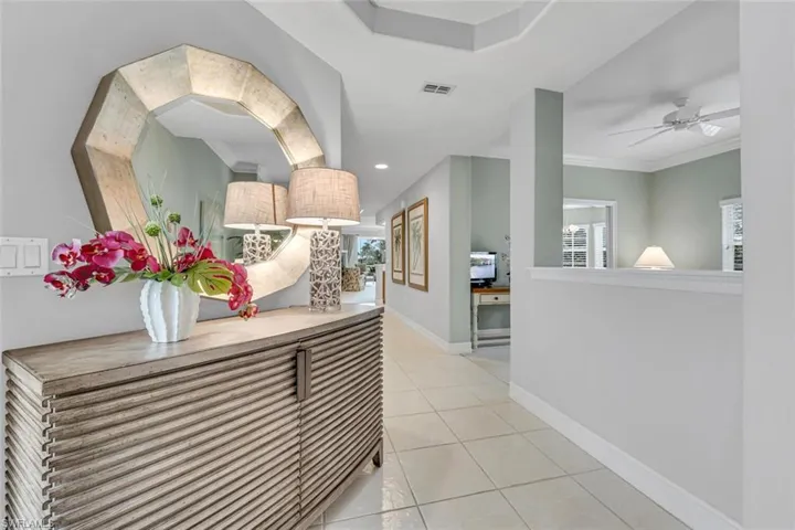 Hallway featuring visible vents, baseboards, ornamental molding, tile patterned floors, and recessed lighting