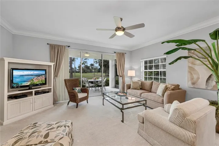 Living area with ornamental molding, light colored carpet, and ceiling fan