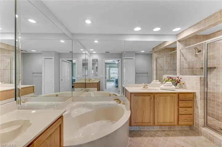 Full bathroom with a stall shower, two vanities, a sink, and a garden tub