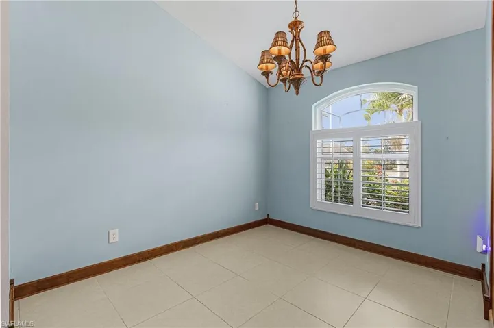 Spare room featuring a notable chandelier, light tile patterned floors, and vaulted ceiling