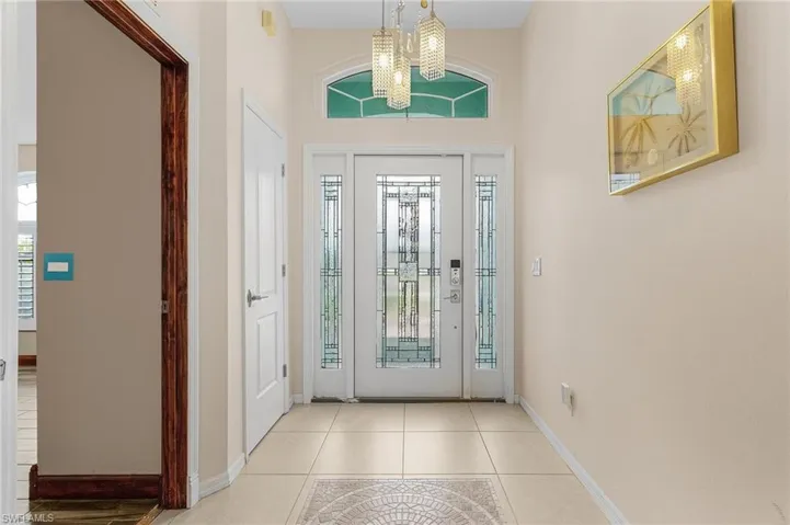 Entryway featuring light tile patterned flooring and a chandelier