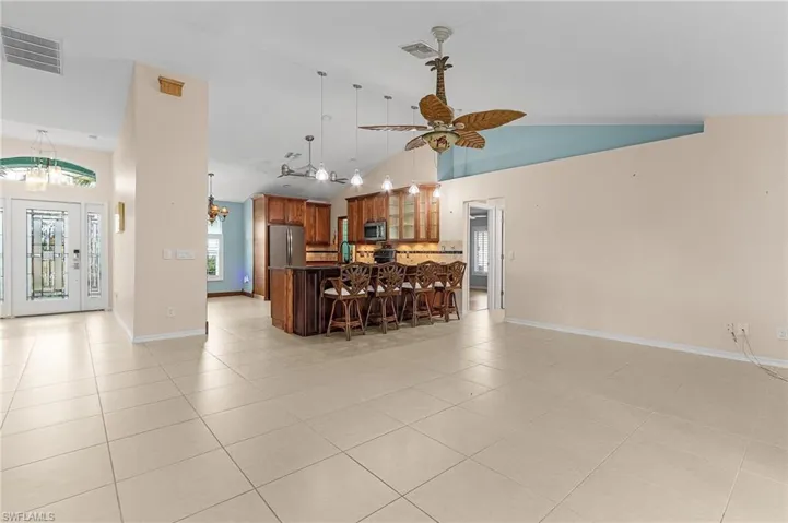Kitchen with light tile patterned flooring, a kitchen breakfast bar, ceiling fan, and appliances with stainless steel finishes