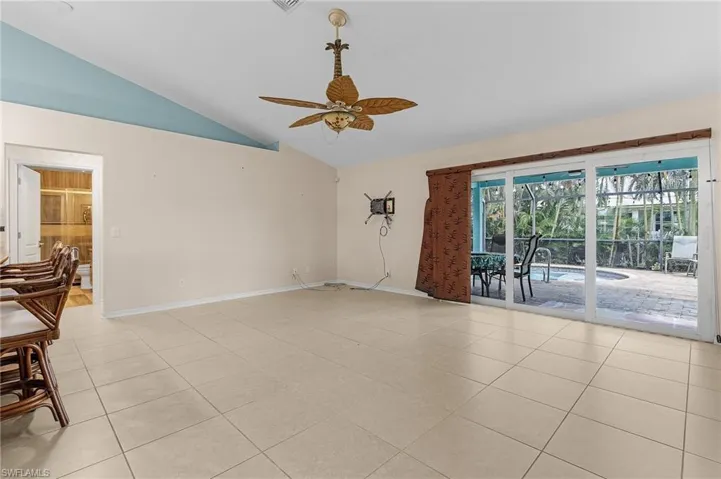 Empty room featuring vaulted ceiling, light tile patterned flooring, and ceiling fan