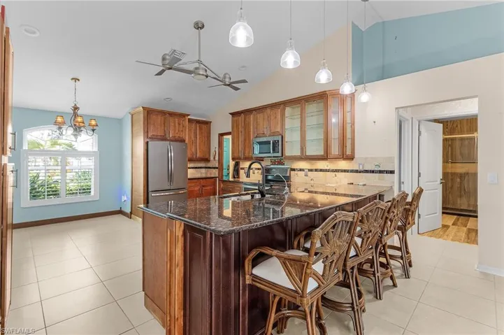 Kitchen with sink, decorative light fixtures, stainless steel appliances, and dark stone counters
