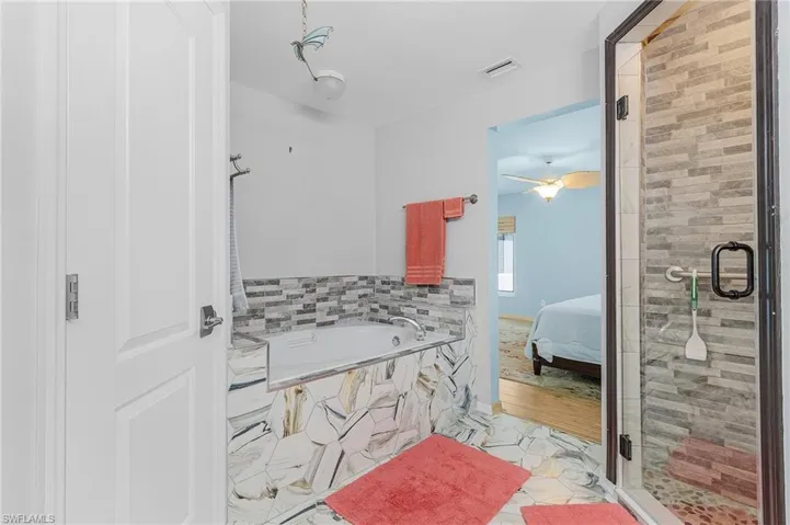 Bathroom with tile patterned flooring, separate shower and tub, and ceiling fan