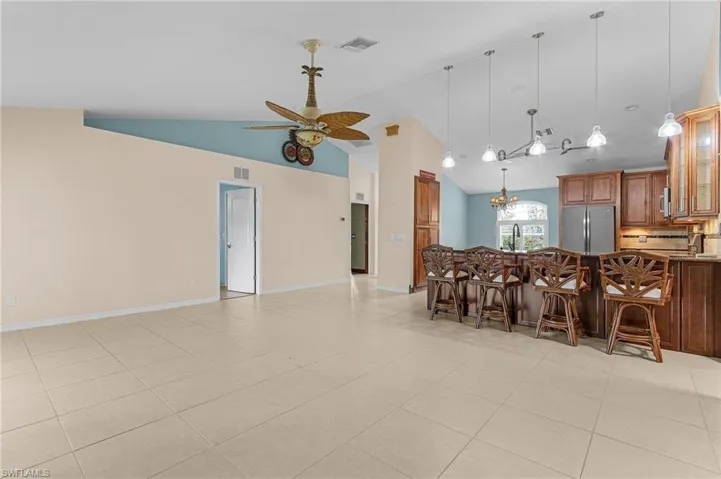 Kitchen with sink, stainless steel fridge, ceiling fan with notable chandelier, a kitchen breakfast bar, and decorative backsplash