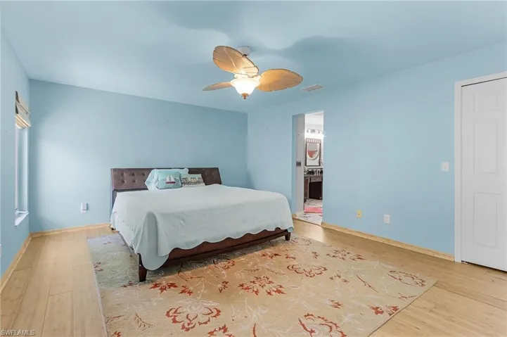 Bedroom with ensuite bath, light hardwood / wood-style floors, and ceiling fan