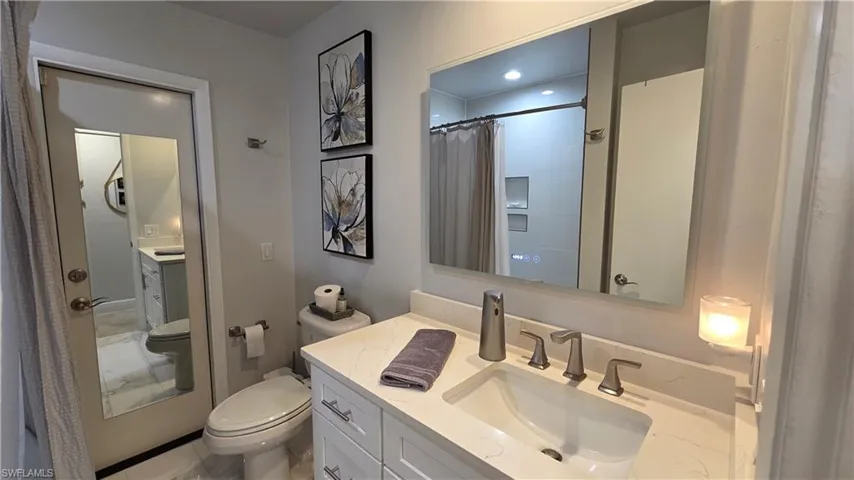 Bathroom featuring a single vanity with a white countertop, undermount sink, and brushed nickel faucet