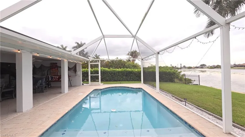 Screened-in pool deck featuring a rectangular swimming pool with blue interior finish and tile coping