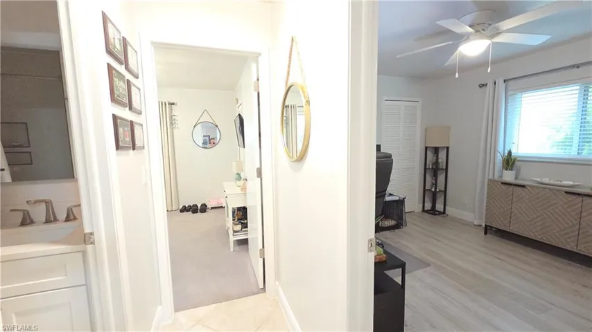 Hallway leading to carpeted room and a separate living area with wood-finish flooring