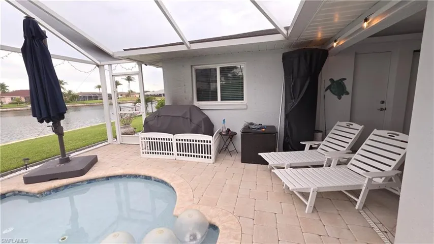 Screened-in lanai featuring a swimming pool with a curved edge, paver decking, and a ceiling-mounted light fixture