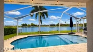Screened lanai featuring a curved swimming pool, paver decking, and a waterfront setting