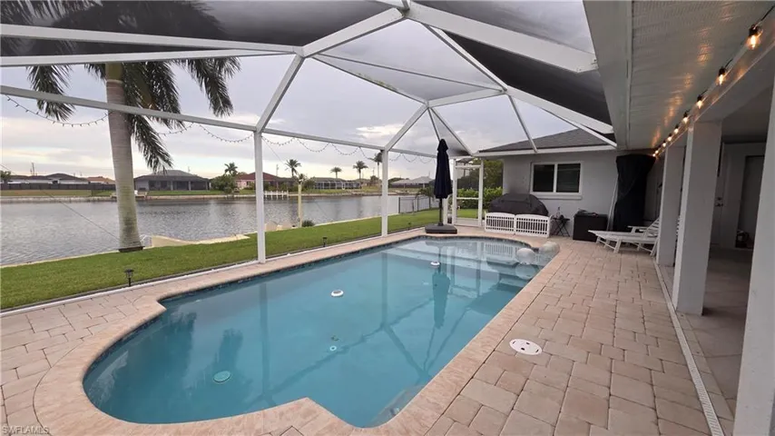 Screened lanai featuring a swimming pool, paver deck, and canal frontage