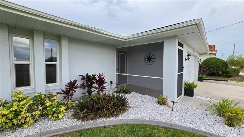 Exterior facade with a covered and screened entry, white gravel landscaping, and established shrubbery