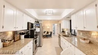Galley kitchen featuring white cabinetry, light-toned countertops, and a full suite of stainless steel appliances