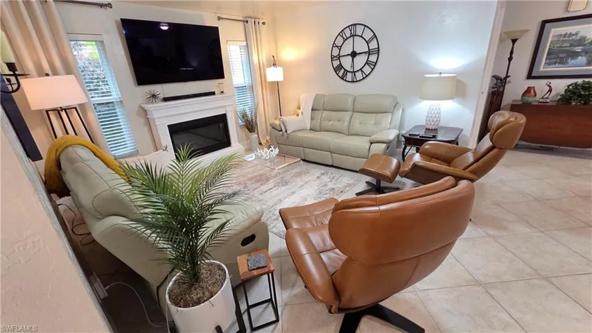 Living area featuring a white mantel fireplace, tile flooring, multiple windows with blinds, and white walls