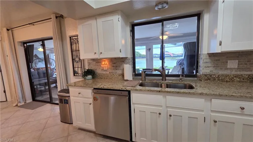Kitchen featuring white shaker-style cabinetry, granite countertops, a double basin sink, and a tile backsplash