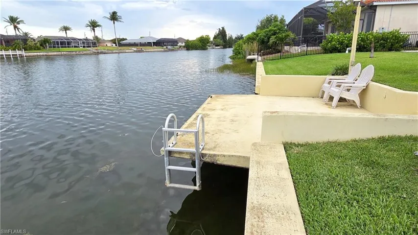 Waterfront concrete dock with a fixed ladder and adjacent elevated concrete patio