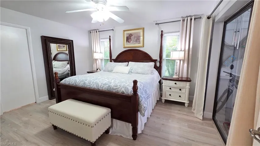 Light-toned wood-finish flooring, a ceiling fan with integrated lighting, and a white interior door