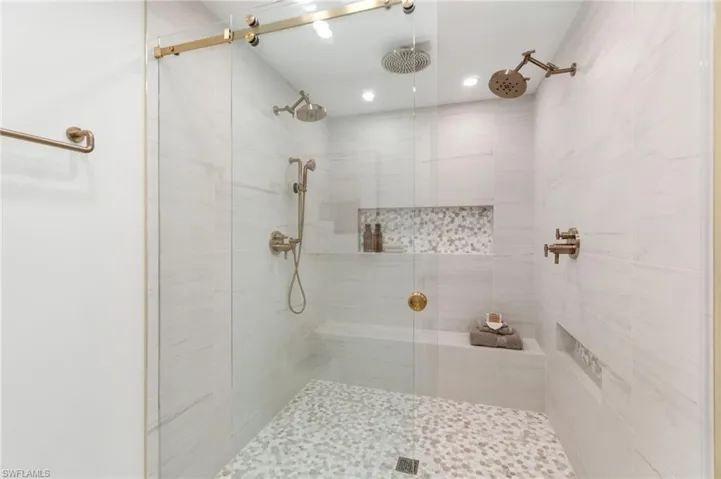 Massive primary shower featuring porcelain tile, with recess and accent stone, finished with rose-gold fixtures