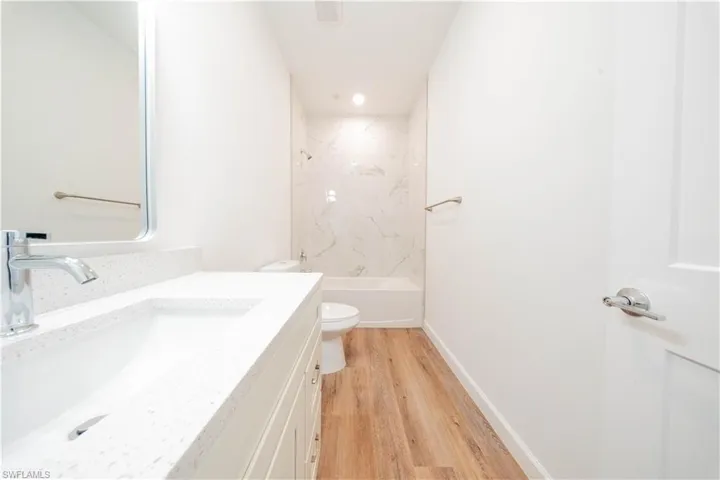 Bathroom with vanity, light wood-style flooring,  shower combination, and recessed lighting