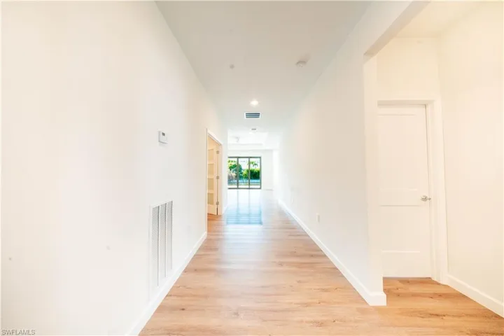 Hallway with light wood finished floors and recessed lighting