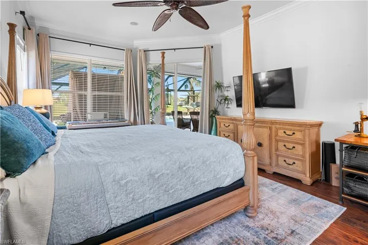 Bedroom featuring dark wood-style flooring, ornamental molding, access to outside, and a ceiling fan