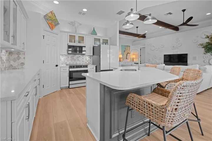 Kitchen with recessed lighting, hanging light fixtures, white cabinetry, glass insert cabinets, and stainless steel appliances