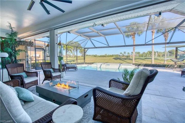 View of patio with a sunroom, a lanai, an outdoor pool, a ceiling fan, and an outdoor living space with a fire pit