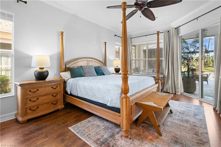 Bedroom with multiple windows, ornamental molding, access to exterior, and dark wood-type flooring