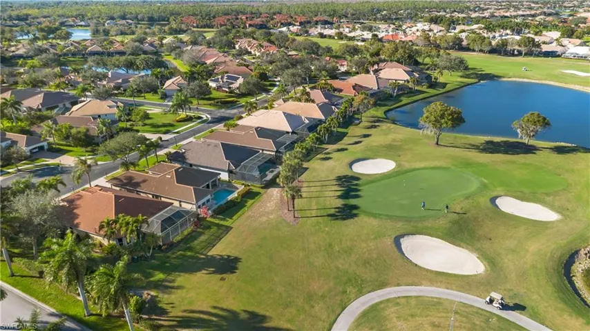 Aerial view of property and surrounding area with a nearby body of water, a golf club, and nearby suburban area