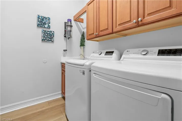 Washroom featuring separate washer and dryer, light wood-style flooring, and cabinet space
