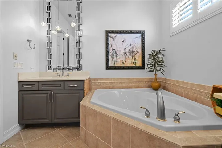 Full bathroom featuring vanity, a bath, and light tile patterned floors