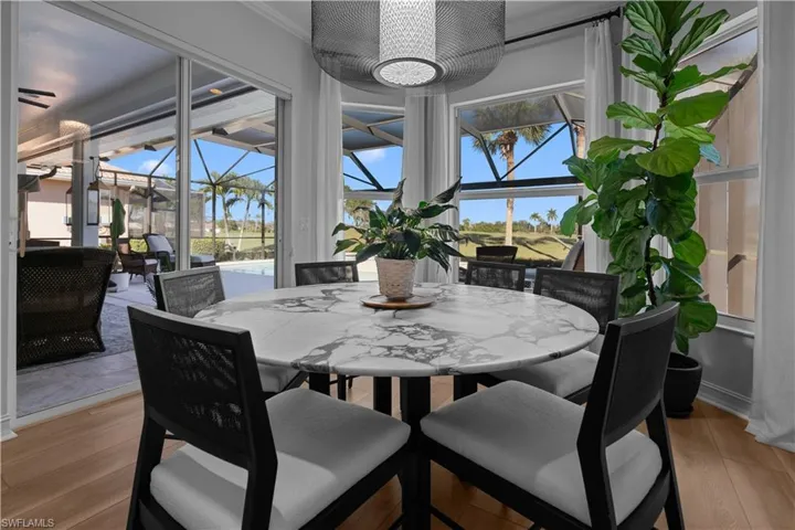 Dining area featuring a sunroom, light wood-style flooring, and ornamental molding