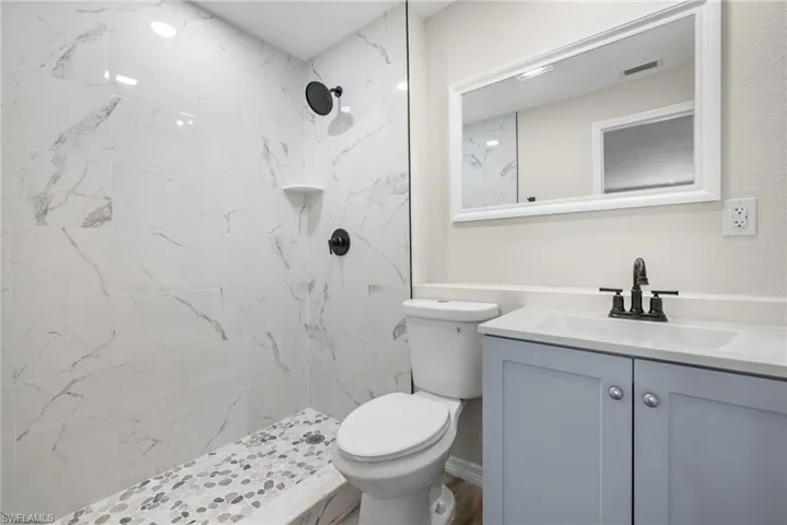 Bathroom with vanity, toilet, and a tile shower