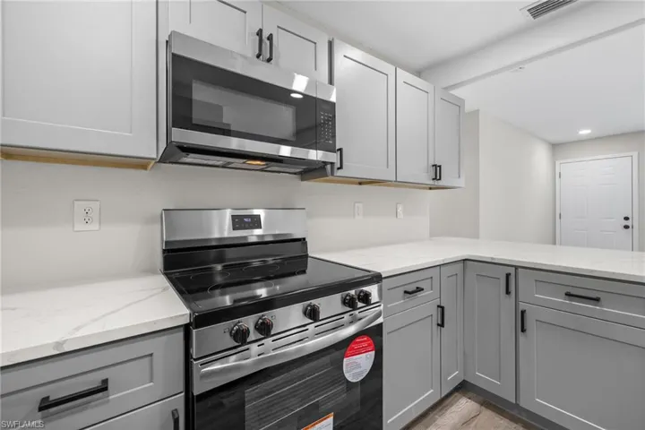 Kitchen with appliances with stainless steel finishes, light hardwood / wood-style floors, and gray cabinetry