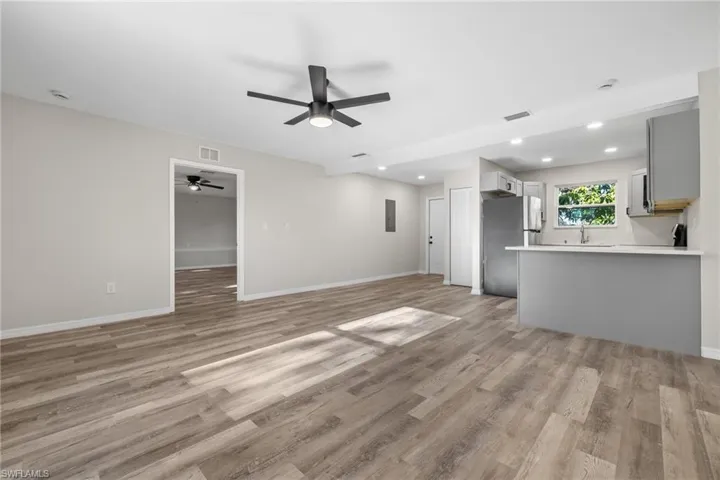 Unfurnished living room featuring light wood-type flooring, ceiling fan, and sink