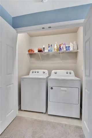 Laundry area featuring light tile patterned floors and independent washer and dryer