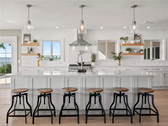 Kitchen featuring open shelves, light wood-style flooring, wall chimney range hood, light countertops, and recessed lighting